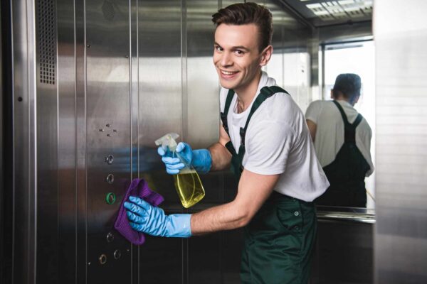 young-cleaning-company-worker-cleaning-elevator-and-smiling-at-camera.jpg