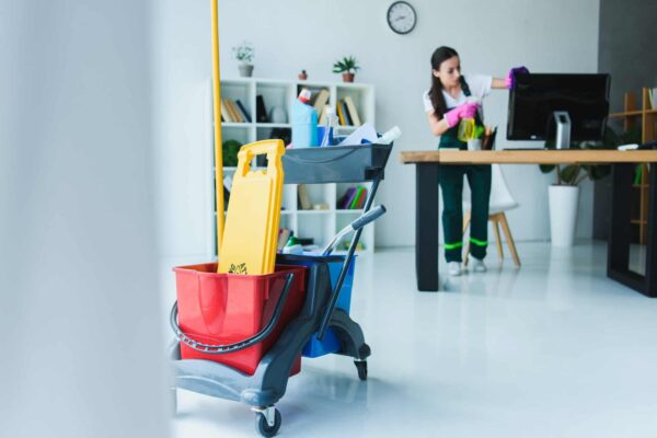 young-female-janitor-cleaning-office-with-various-cleaning-equipment